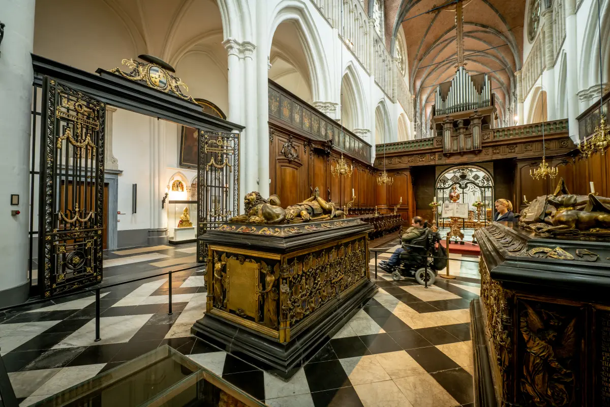 man in an electric wheelchair visiting the choir of the Church of Our Lady with the tombs of Charles the Bold (left) and Mary of Burgundy (right).\n