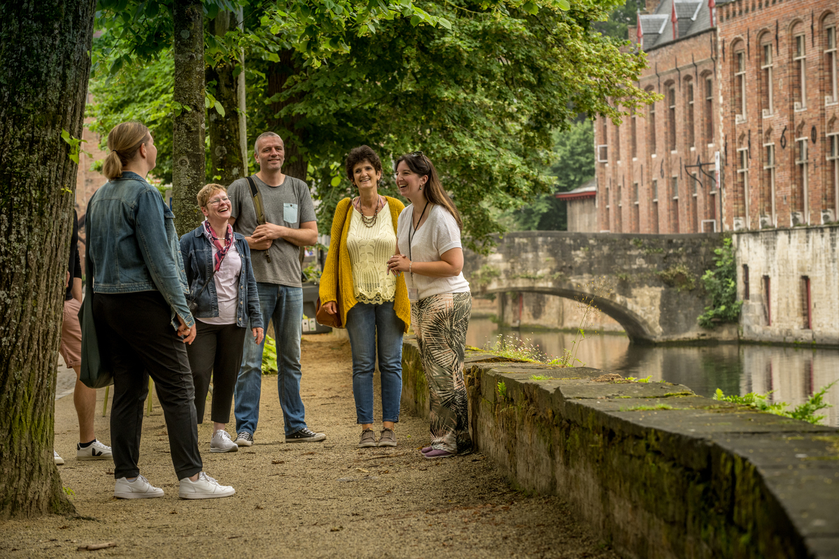 Group of visitors standing around a guide giving explanations along Groenerei, everyone is smiling
